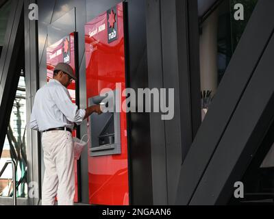 A middle aged South Asian man using a NAB smart ATM in Melbourne Stock Photo