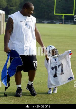 Carolina Panthers Kris Jenkins left walks as his son Kris 2 wears his dad s jersey and helmet after practice during the team s training camp in Spartanburg S.C. Tuesday Aug. 10 2004. AP Photo Chuck Bu...