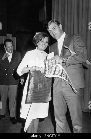 Detroit Tigers ace pitcher Denny McLain holds a plastic chicken under his  arm as he signs an autograph for nurse J. Adams, shortly before he performs  an organ recital at a downtown