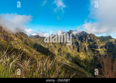 Steep, green and rocky mountains in Madeira - view from Vereda do Encumeada hiking trail between Encumeada pass and Pico Ruivo hill during beautiful s Stock Photo