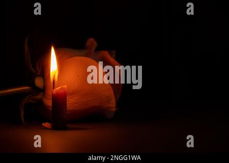 a candle flame and next to one rose in the dark close-up Stock Photo