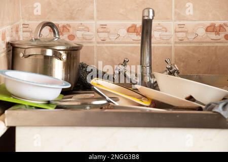 a pile of dirty dishes in the sink in the kitchen in the apartment Stock Photo