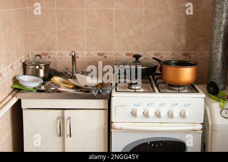 full sink dirty dishes and a gas stove in the kitchen in the apartment Stock Photo