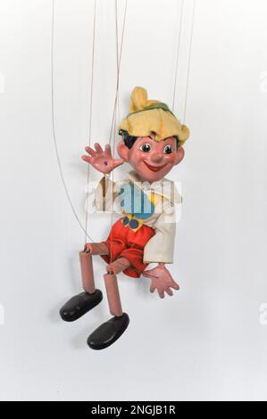 A vintage marionette puppet on a string of Pinocchio, set against a white background Stock Photo