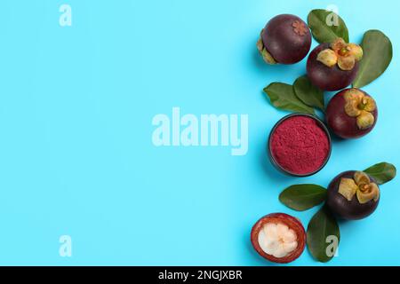 Purple mangosteen powder and fruits on light blue background, flat lay. Space for text Stock Photo