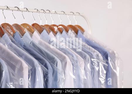 Premium Photo  Wooden hangers with clothes in dry cleaning bags closeup