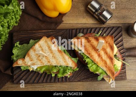 Wooden board with tasty sandwiches on table, flat lay Stock Photo