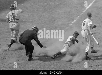 Jackie Robinson, Dodgers' second baseman, crosses home plate on a steal  from third as Giants' catcher Walker Cooper (5) fires the ball to third  base in the 7th inning of the Brooklyn 