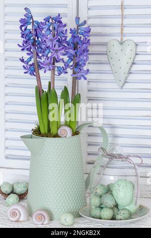 floral arrangement with purple hyacinth flowers in vintage jug and easter eggs Stock Photo