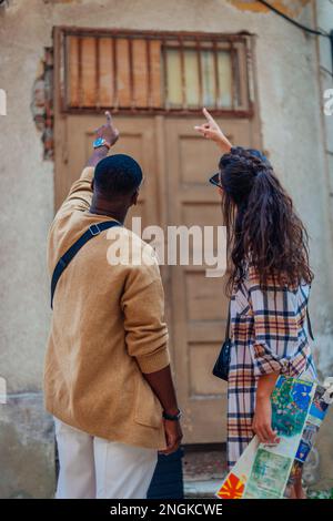 A man is trying to explain something to his girlfriend. They are pointing at the same direction Stock Photo
