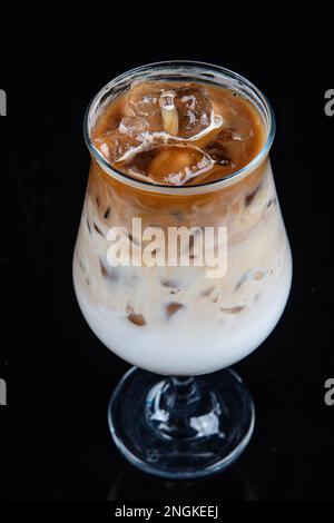 https://l450v.alamy.com/450v/2ngkeej/iced-coffee-mug-iced-coffee-is-poured-into-a-tall-glass-with-cream-cold-summer-drink-on-black-background-with-copy-space-2ngkeej.jpg