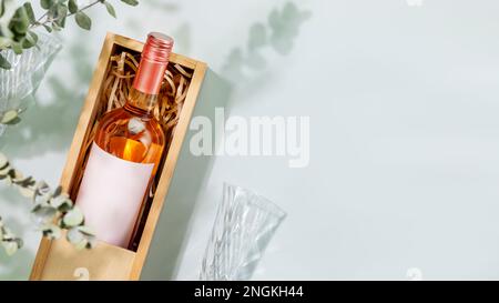 Rose wine. Bottle of pink wine with glasses on blue background with eucalyptus green leaves and shadows. Summer romantic still life with bottle of low Stock Photo