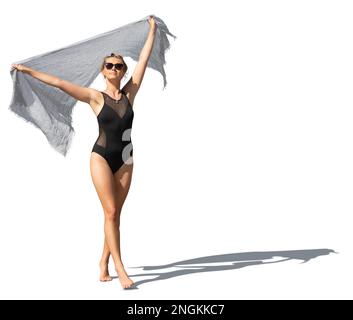 Beautiful young woman in black swimsuit walking and holding her light beach towel up in the air in the wind isolated on white background Stock Photo