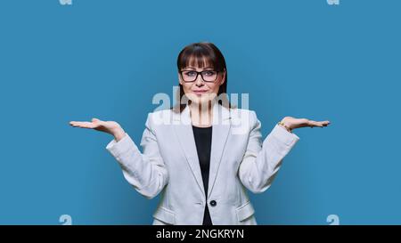 Business woman holding two hands with empty open palms on blue background Stock Photo