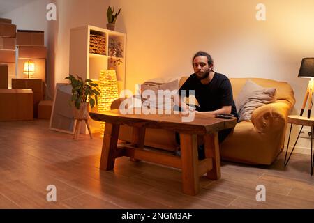 Sad man sitting on couch at home. Stock Photo
