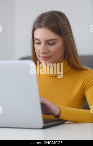 Young adult woman working on laptop computer. Portrait of beautiful white female in 20s studying online with modern notebook pc Stock Photo