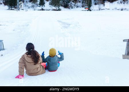 two girls preparing to slide down the snow hill in the mountains Stock Photo