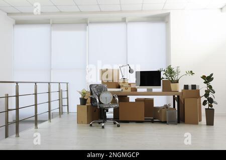 Cardboard boxes, computer and furniture in new office. Moving day Stock ...