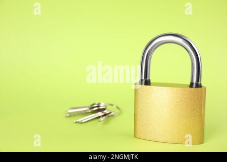 Modern padlock and keys on light green background. Space for text Stock Photo