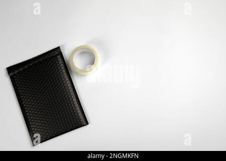 Padded envelope with bubble wrap and tape on light background, flat lay. Space for text Stock Photo