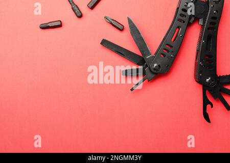 Compact portable black multitool and details on red background, flat lay. Space for text Stock Photo