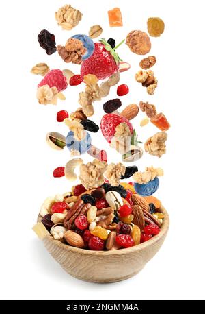 Delicious granola, nuts and berries falling into bowl on white background. Healthy snack Stock Photo