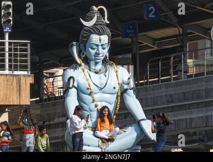 A girl is seen sitting on the lap of the statue of Hindu god Shiva on the roof of a temple on the occasion of Mahashivratri (Great Night of Shiva) in Mumbai. Mahashivratri (Great Night of Shiva) is celebrated by Hindus to commemorate the wedding of god Shiva to goddess Parvati. Devotees fast on this day and seek blessings from god Shiva. Stock Photo