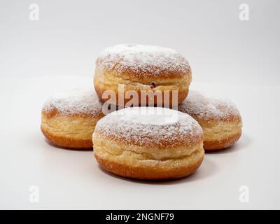 Freshly baked and dusted with powdered sugar German donuts. Donut berliner or krapfen on white background. Stock Photo