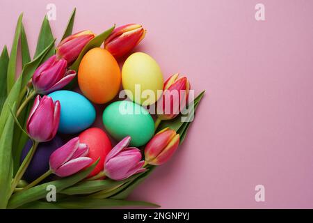 Colorful tulip flowers and easter eggs on pink background. Top view with copy space. Happy easter greeting card. Stock Photo
