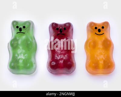 three gummy bears showing smiling face and two unhappy faces.  Indicating happy outlook and mental health Stock Photo