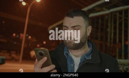 Bearded Tall Young Man Messaging on Phone in the Snowy Scenery Stock Photo
