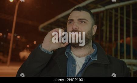 Bearded, Tall Young Man Answering Incoming Call in Winter Scenery Stock Photo