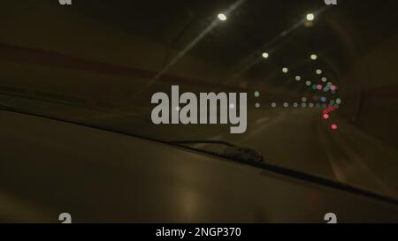 Driving through a blurry tunnel road with low visibility: A mesmerizing view from the front window of a moving car in the dead of night Stock Photo