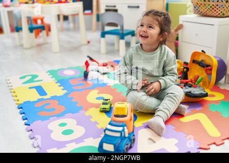 Adorable hispanic toddler playing with car toy sitting on floor at ...