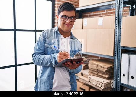 Down syndrome man ecommerce business worker write on clipboard at office Stock Photo