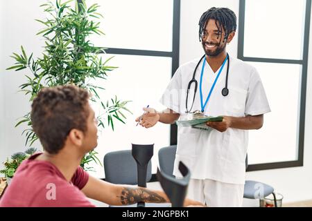 Two men physiptherapist and patient having medical consultation using crutches at hospital waiting room Stock Photo