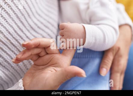 Mother and son lying on bed holding finger at home Stock Photo