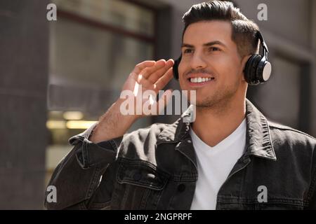 Handsome man with headphones listening to music on city street Stock Photo