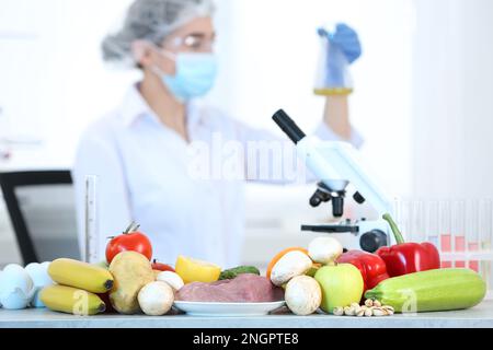 Fresh vegetables, fruits, meat on table and scientist proceeding quality control in laboratory Stock Photo