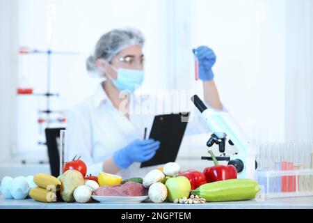 Fresh vegetables, fruits, meat on table and scientist proceeding quality control in laboratory Stock Photo