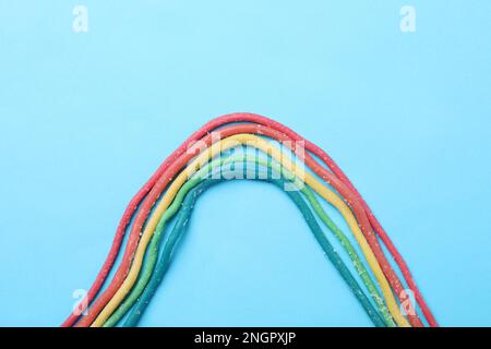 Rainbow of gummy strings on light blue background, flat lay Stock Photo
