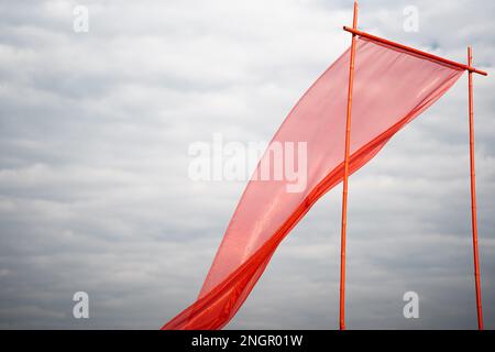 Red silk cloth flying or waving in air with white clouds Stock Photo
