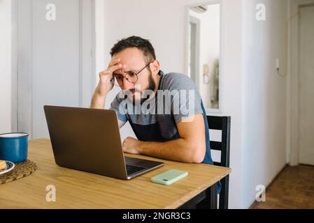 Man using his laptop holding his head. Stock Photo