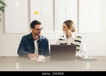 Smiling businesspeople preparing to join an online meeting on a laptop. Two happy businesspeople connecting with their global clients in a creative of Stock Photo