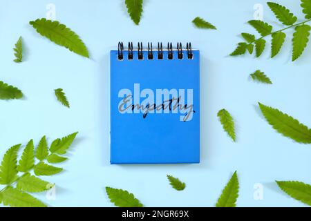 Empathy concept. Word written on blue notepad. Beautiful minimalist flat lay composition. Stock Photo