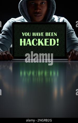 Your network could be next. a young hacker using a laptop with the words You have been hacked on it. Stock Photo