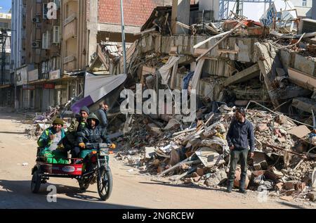 Adiyaman, T¨¹rkiye. 18th Feb, 2023. People pass a collapsed building in Adiyaman, T¨¹rkiye, Feb. 18, 2023. The death toll from two major earthquakes that struck southeastern T¨¹rkiye on Feb. 6 has risen to 40,642, the country's disaster agency said Saturday. Credit: Mustafa Kaya/Xinhua/Alamy Live News Stock Photo