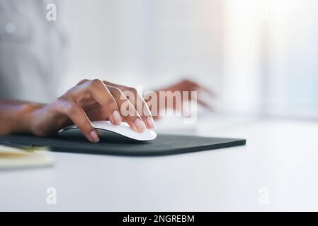 Scrolling and clicking through a world of opportunity. Closeup shot of an unrecognizable woman using a computer mouse in an office. Stock Photo