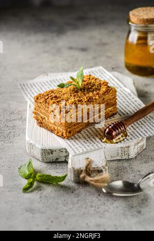 honey cake on a gray background. Cakes with honey and butter cream, decorated with mint Stock Photo