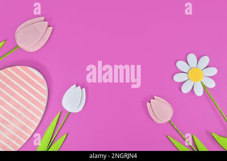 Felt tulip and daisy spring flowers and wooden Easter egg on purple background Stock Photo